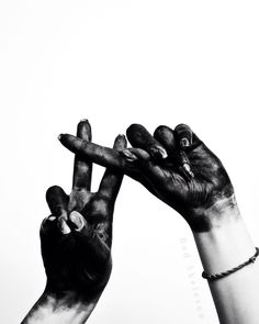 two hands holding something up in the air with their fingers painted black and white,