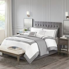 a bed with white and grey comforters in a bedroom