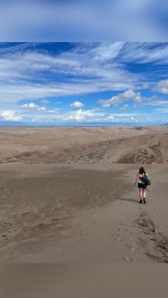 a woman is walking through the sand dunes