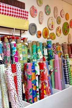 many different colored umbrellas are on display in a store with clocks and wall hangings behind them