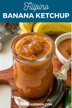 a banana ketchup in a glass jar on a cutting board with bananas and spoons