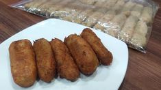 some fried food on a white plate next to a bag of breaded pastries