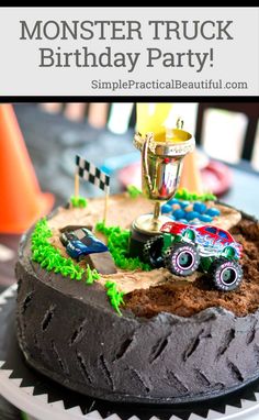 a monster truck birthday cake with dirt and grass on the bottom, topped with a trophy