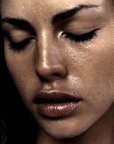 a close up of a woman with her eyes closed and water droplets on her face