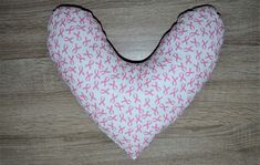 a pink and white heart shaped pillow sitting on top of a wooden floor