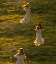 a woman in white dress walking across a lush green field with her hair blowing in the wind