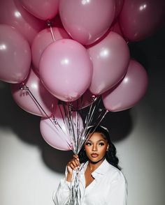 a woman holding bunches of balloons in front of her face