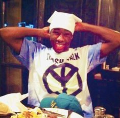 a man sitting at a table with food in front of him and his hands on his head