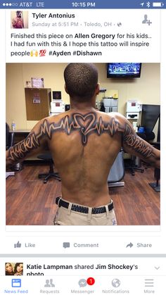 the back of a man with tattoos on his arms and shoulder, standing in front of a computer desk