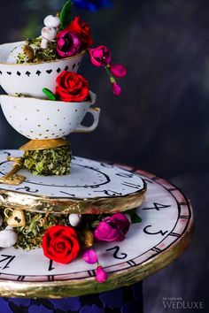 a stack of teacups with flowers on them sitting on top of a clock