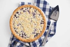 a pie with blueberries and crumbled toppings sits on a napkin next to a fork