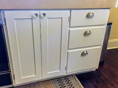 a kitchen with white cabinets and wood flooring on the side of the counter top