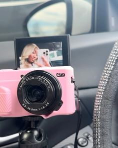 a pink camera sitting on top of a car dashboard