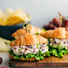 two croissant sandwiches with lettuce and chicken salad on a cutting board