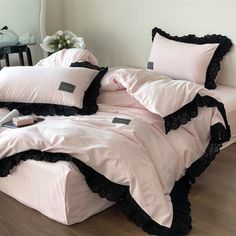 a bed with pink sheets and black ruffles