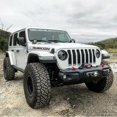 a white jeep parked on top of a dirt field