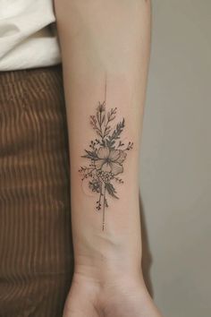 a woman's arm with a flower tattoo on the left side of her wrist