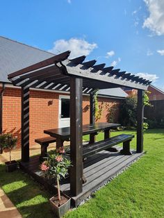 a wooden picnic table sitting under a pergolated roof next to a brick building