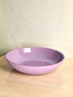 a purple bowl sitting on top of a wooden table