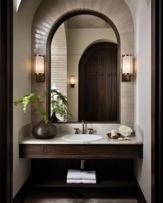 a bathroom sink with a mirror and vase on it's side, in front of an arched doorway