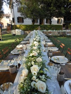 the long table is set with white flowers and greenery for an elegant dinner party