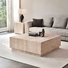 a living room with a couch, coffee table and lamp on the floor in front of a window