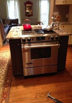 a stove top oven sitting in the middle of a kitchen next to a table with utensils on it