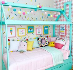 a child's bed with lots of pillows and decorations on the wall above it