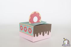 a box with a donut on top of it sitting on a white table next to a unicorn