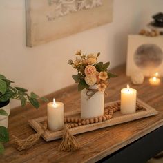 three candles are sitting on a tray with flowers