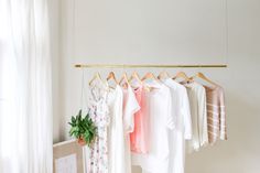 there are many different clothes hanging on the rack in this room and one is white