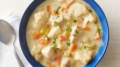 a blue bowl filled with chicken and dumplings next to a white napkin on top of a table