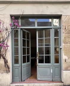 an open door to a building with flowers growing out of it