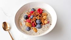 a bowl of oatmeal topped with berries and nuts next to a spoon