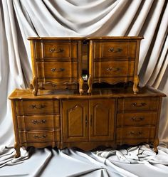 two wooden dressers sitting next to each other on top of a white cloth covered floor