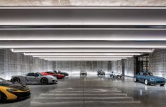 several sports cars are lined up in a large room with concrete walls and flooring