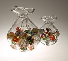 two glass vases with different colored marbles in them