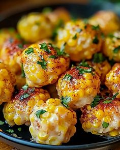 a black plate topped with corn covered in seasoning and garnished on top of a wooden table