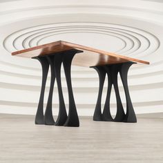 two tables with wooden tops in front of a white circular wall and wood flooring