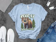 This Funny Bear Pun T-Shirt features a cute bear illustration with the phrase "Bear-ly Breaking A Sweat." Perfect for nature lovers and anyone who enjoys a good pun, this adorable animal tee is a great addition to any casual wardrobe. Ideal for outdoor enthusiasts and those who appreciate clever humor, it's comfortable and stylish for everyday wear. Show your love for bears and make a statement with this unique and charming t-shirt. Product Features: Fabrication: 100% Airlume combed and ring-spun cotton, 32 single 4.2 oz. (Ash - 99% Airlume combed and ring-spun cotton, 1% poly) Seams: Side-seamed Fit: Retail Fit Sizing: Unisex Sizing Label: Tear away label Graphic Tee With Bear Design And Crew Neck, Bear Puns, Funny Bears, Bear Illustration, Bear Shirt, Cute Bears, Casual Wardrobe, Favorite Things Gift, Clothing Items