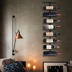 a living room filled with furniture and bottles of wine on the wall next to a lamp