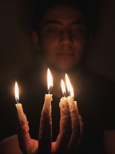 a person holding three candles in their hands