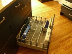 an open drawer in the middle of a wooden floor next to a kitchen counter top