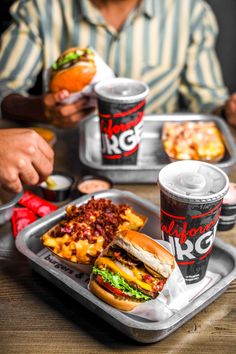 a man sitting at a table with two trays of food and drinks in front of him