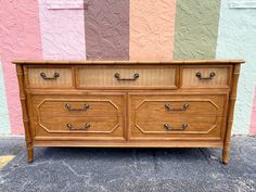 a wooden dresser with drawers in front of a colorful wall