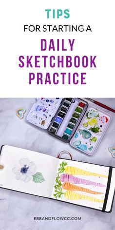 an open sketchbook with watercolors and pencils on the table next to it