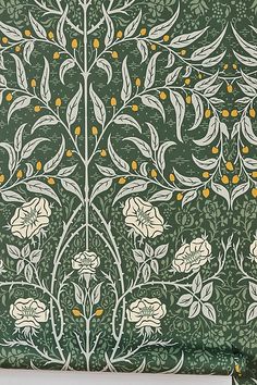 a green and white wallpaper with flowers and leaves in the center, on top of a wooden table