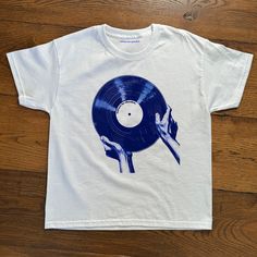 "The Record" Baby Tee Baby tee featuring iconic record graphic.  - 100% cotton - Classic fit - Runs true to size (refer to size chart) - Tear-away label - Y2K Vintage Streetwear Trending Fashion - Environmentally sustainable made-to-order system Baby tee's were popularised in the '90s, characterised by it's very short sleeves and slightly cropped body, creating a very flattering feminine shape. It originated from the skater/raver scene and was linked to the era's popular child-like fashion.  Ple Cool Graphic Tees Vintage, White Music-themed Crew Neck T-shirt, Unisex Blue T-shirt For Streetwear, Unisex Music-themed Tops With Screen Print, Unisex Music-themed Screen Print Top, Music-themed Unisex Screen Print Top, Unisex Music-themed Tops With Graphic Print, White T-shirt With Heat Transfer Vinyl For Streetwear, Music-themed White Graphic T-shirt