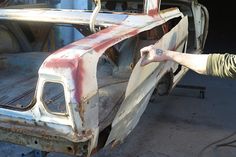 an old car being worked on by a man with his hand out to the side