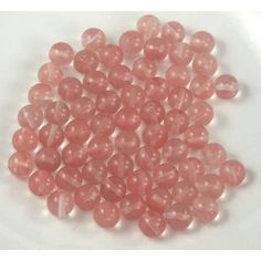 some pink beads are on a white surface and there is no image in the top right corner